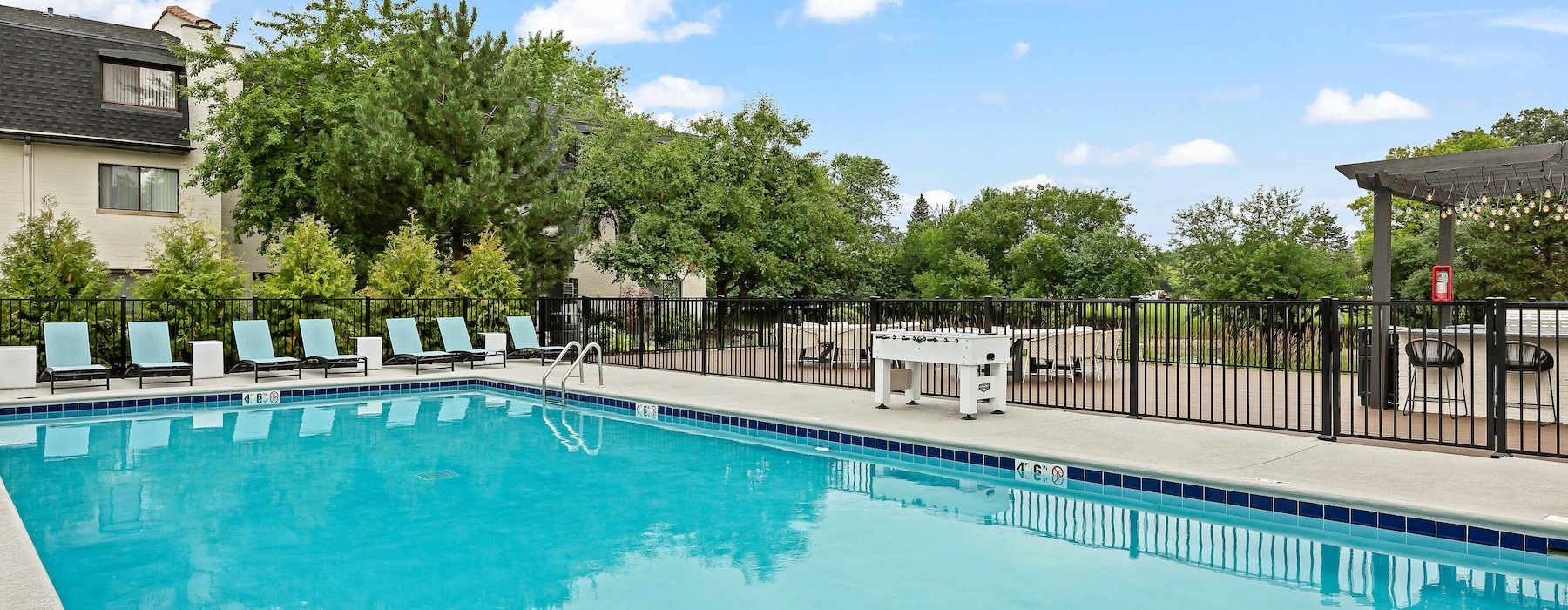 a swimming pool with chairs and a fence around it